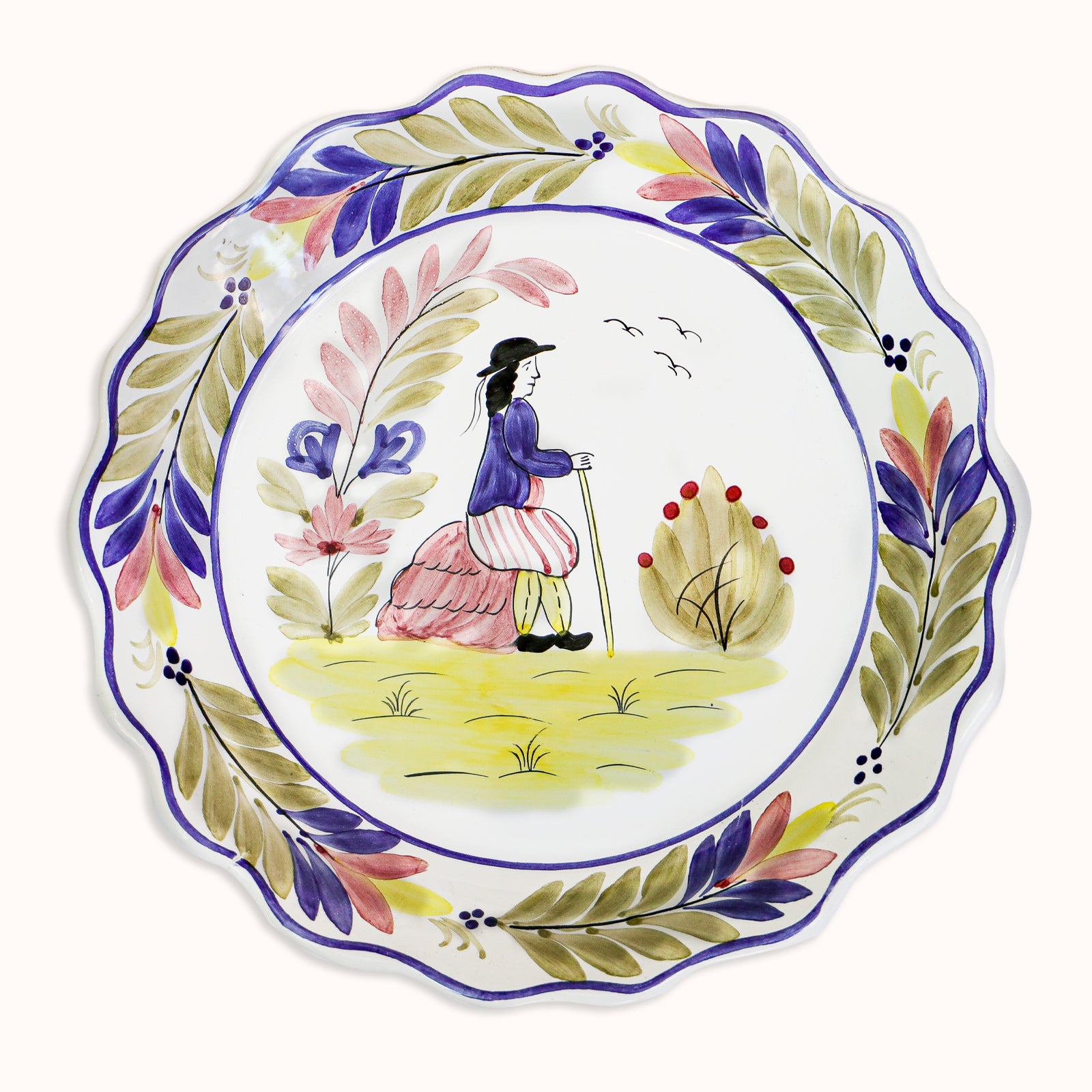 A vintage ceramic majolica plate with a hand-painted depiction of a man, scalloped borders, and floral patterns, available at Wildschut Antiques