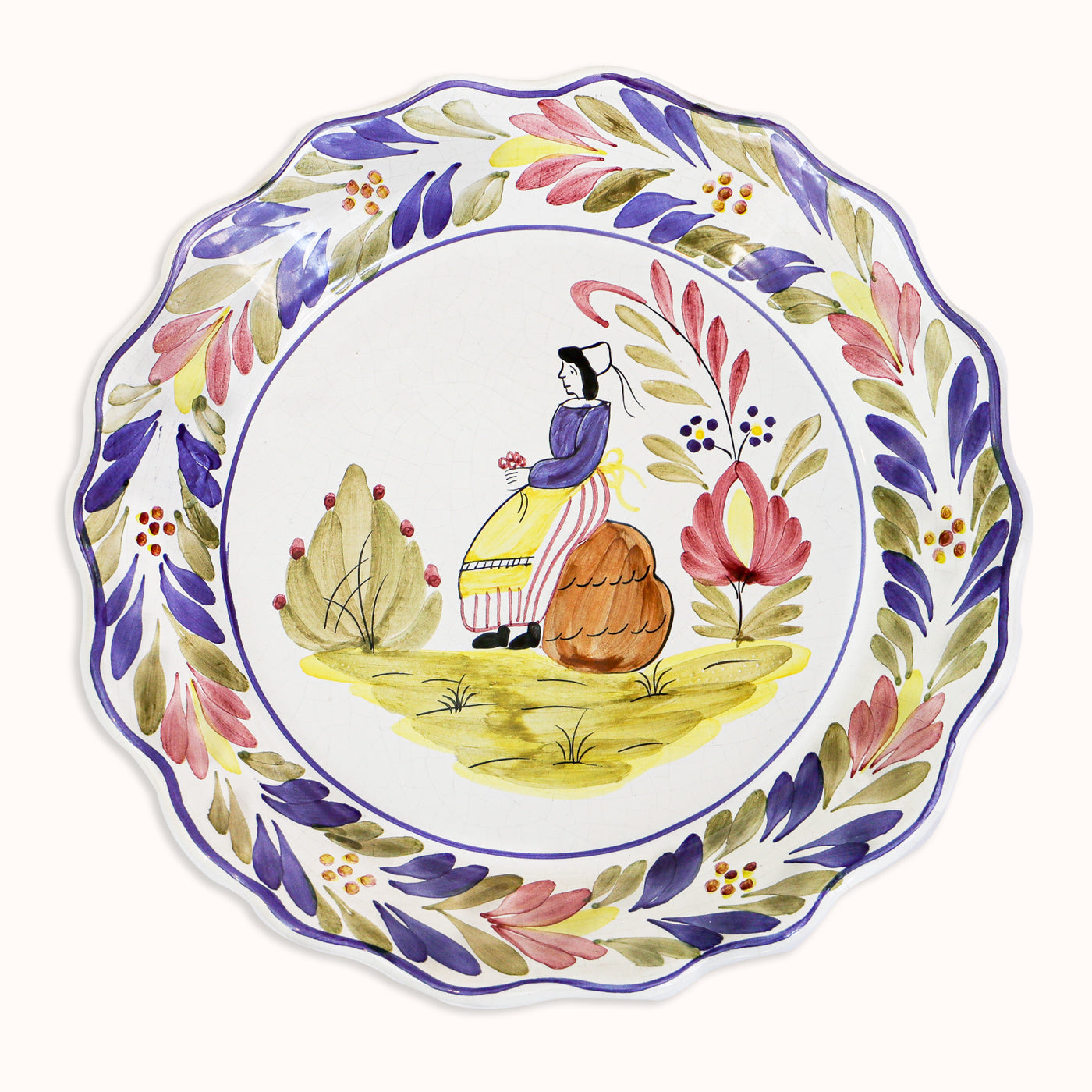 A vintage ceramic majolica plate with a hand-painted depiction of a woman, scalloped borders, and floral patterns, available at Wildschut Antiques