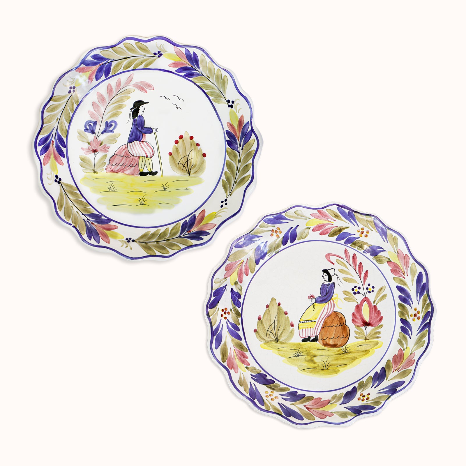 A set of two vintage ceramic majolica plates with hand-painted depictions of a man and a woman, scalloped borders, and floral patterns, available at Wildschut Antiques