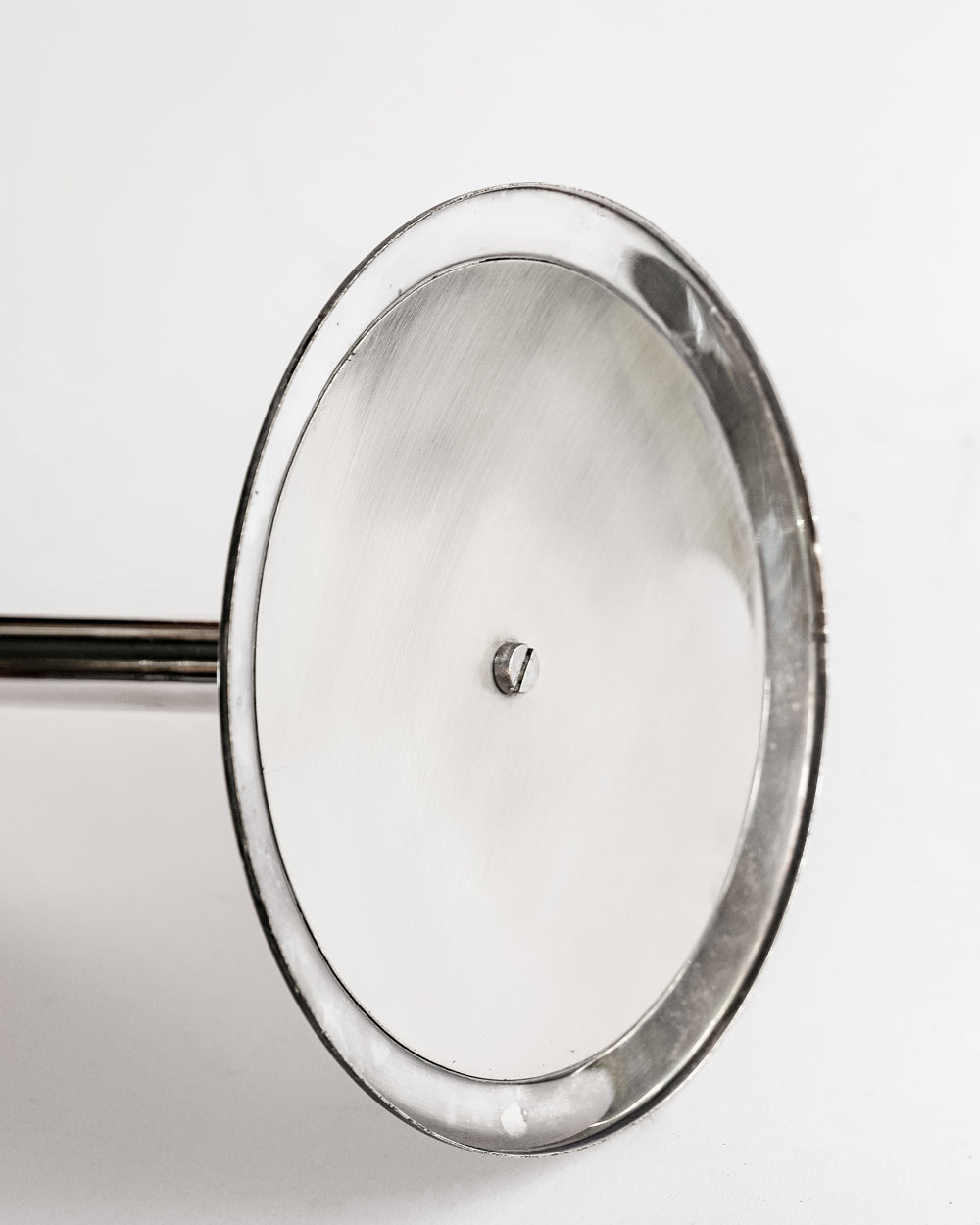 Close-up of the foot of a vintage silver plated champagne bucket stand, with a sleek, cylindrical shape and a reflective surface