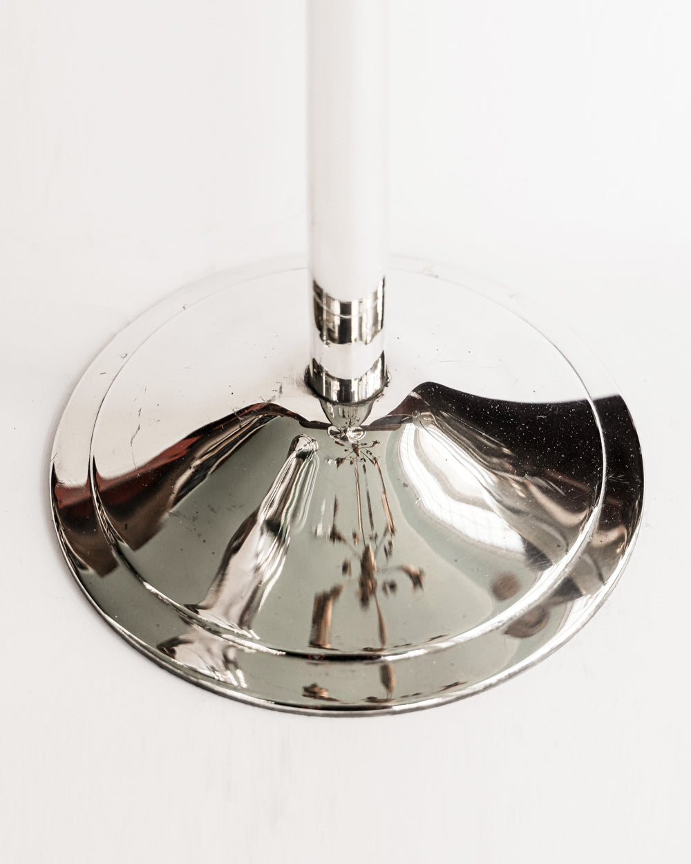 Close-up of the foot of a vintage silver plated champagne bucket stand, with a sleek, cylindrical shape and a reflective surface