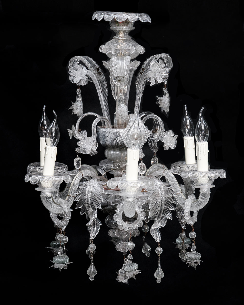 A clear, hand-blown glass Venetian chandelier with six lights and intricate details, set against a black background, available at Wildschut Antiques