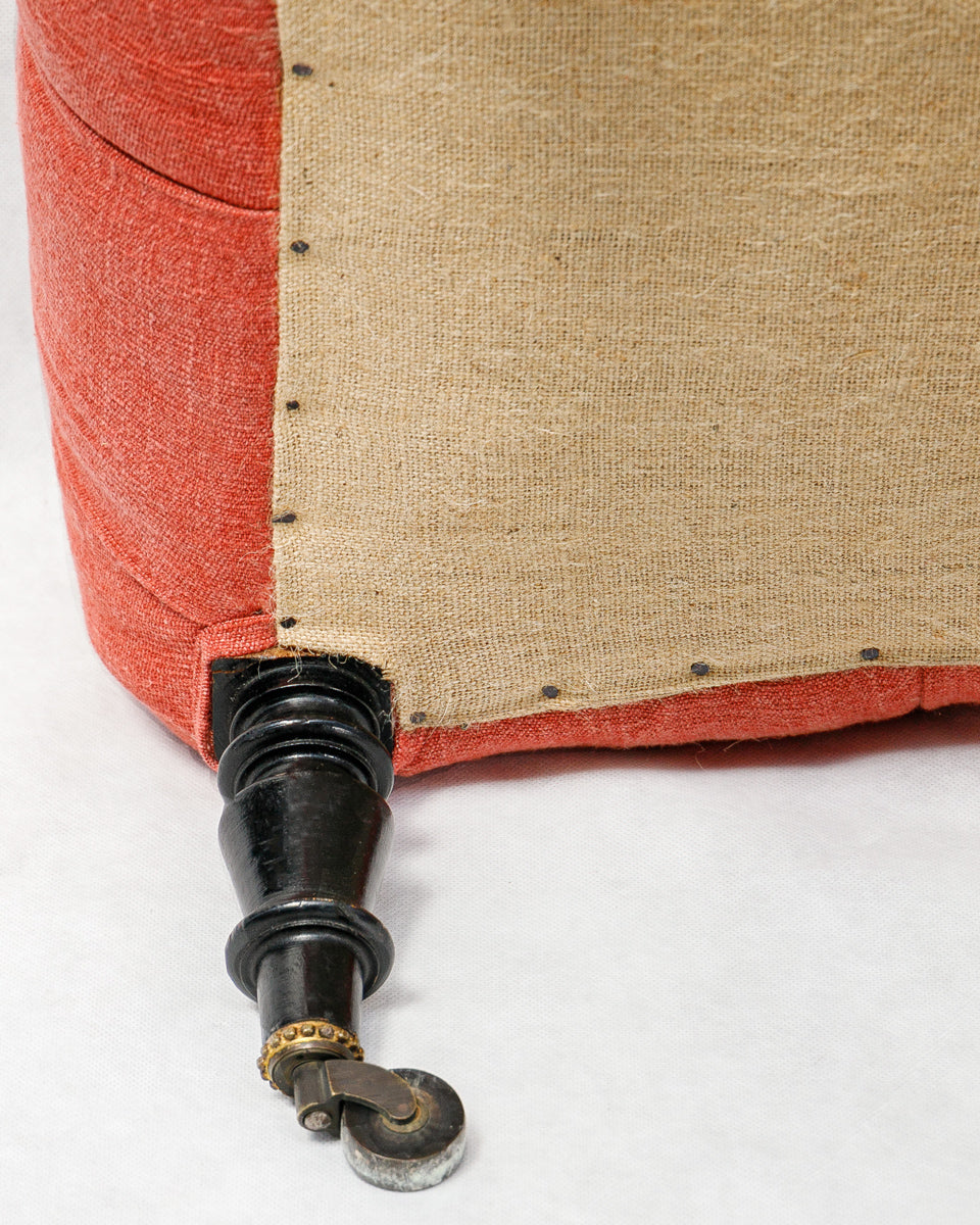 Close-up of a piece of furniture with red fabric and black metal legs on a white background