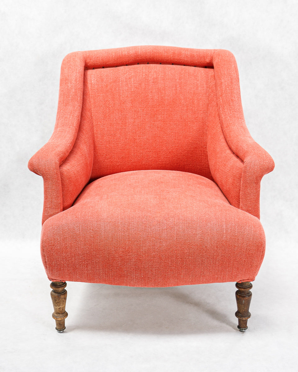 Coral antique French armchair with wooden legs on a white background.