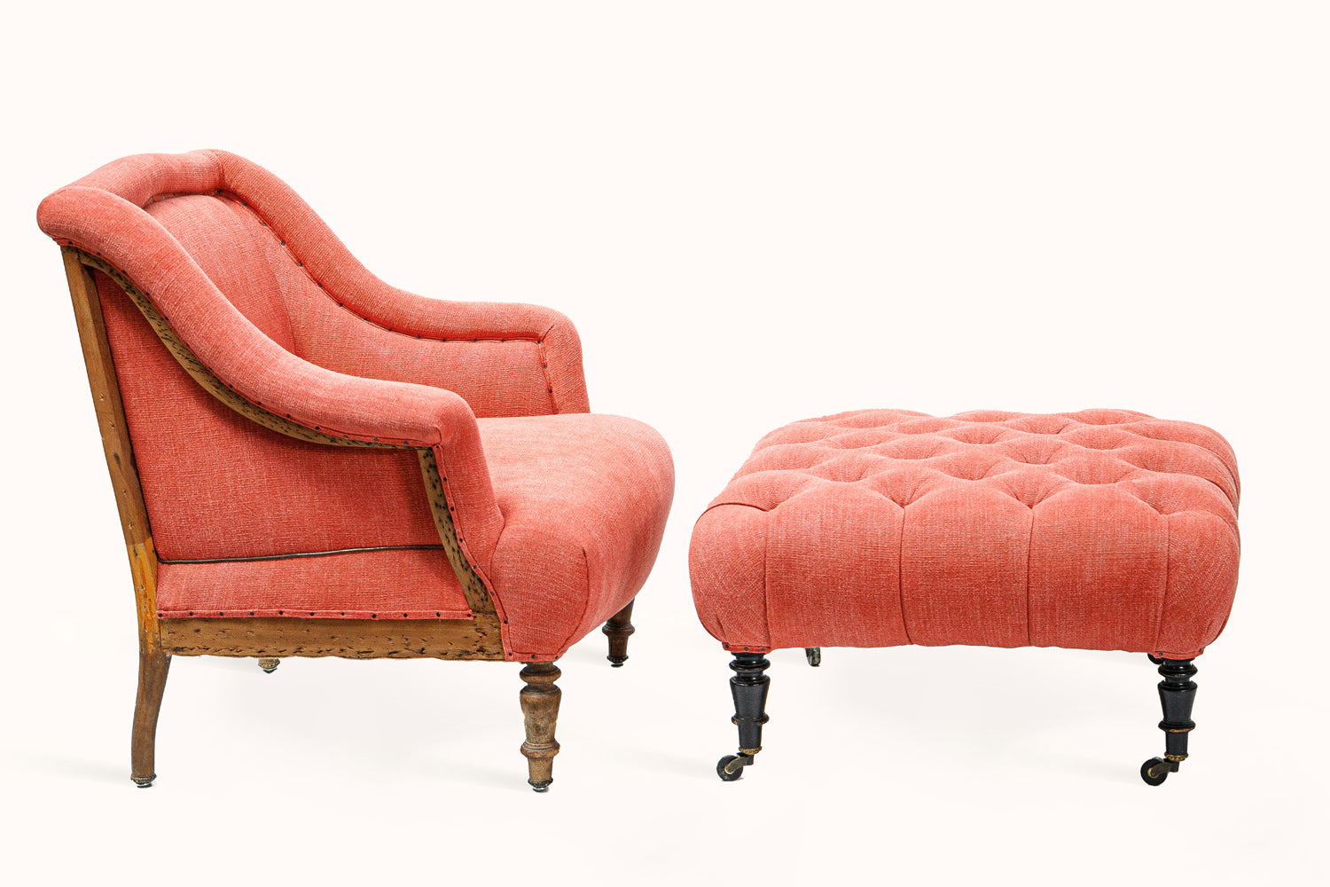 Sideview of a French antique Napoleon III-style armchair with matching ottoman, upholstered in soft coral red fabric, from Wildschut Antiques
