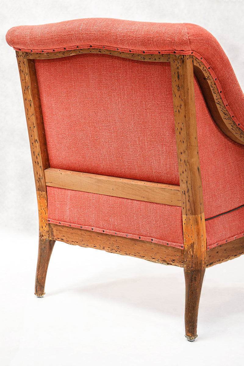 Coral linen upholstered chair with wooden frame on a white background