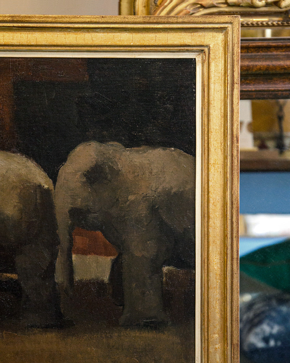 Painting of elephants in a gold frame with a blurred background. Close-up of an oil painting of two elephants in a circus setting, signed by Toon Kelder