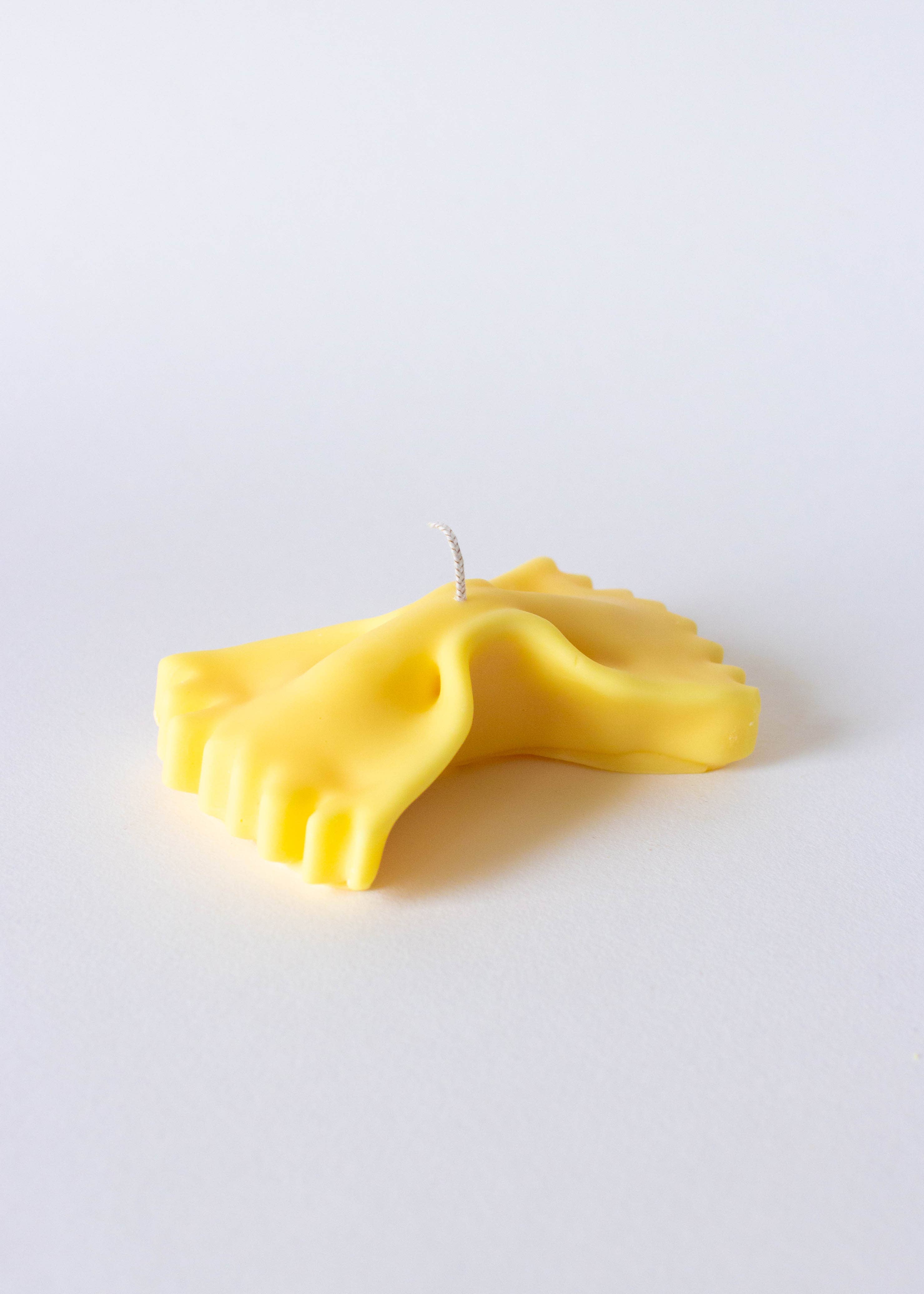Yellow bow-shaped farfalle pasta candle on a white background.