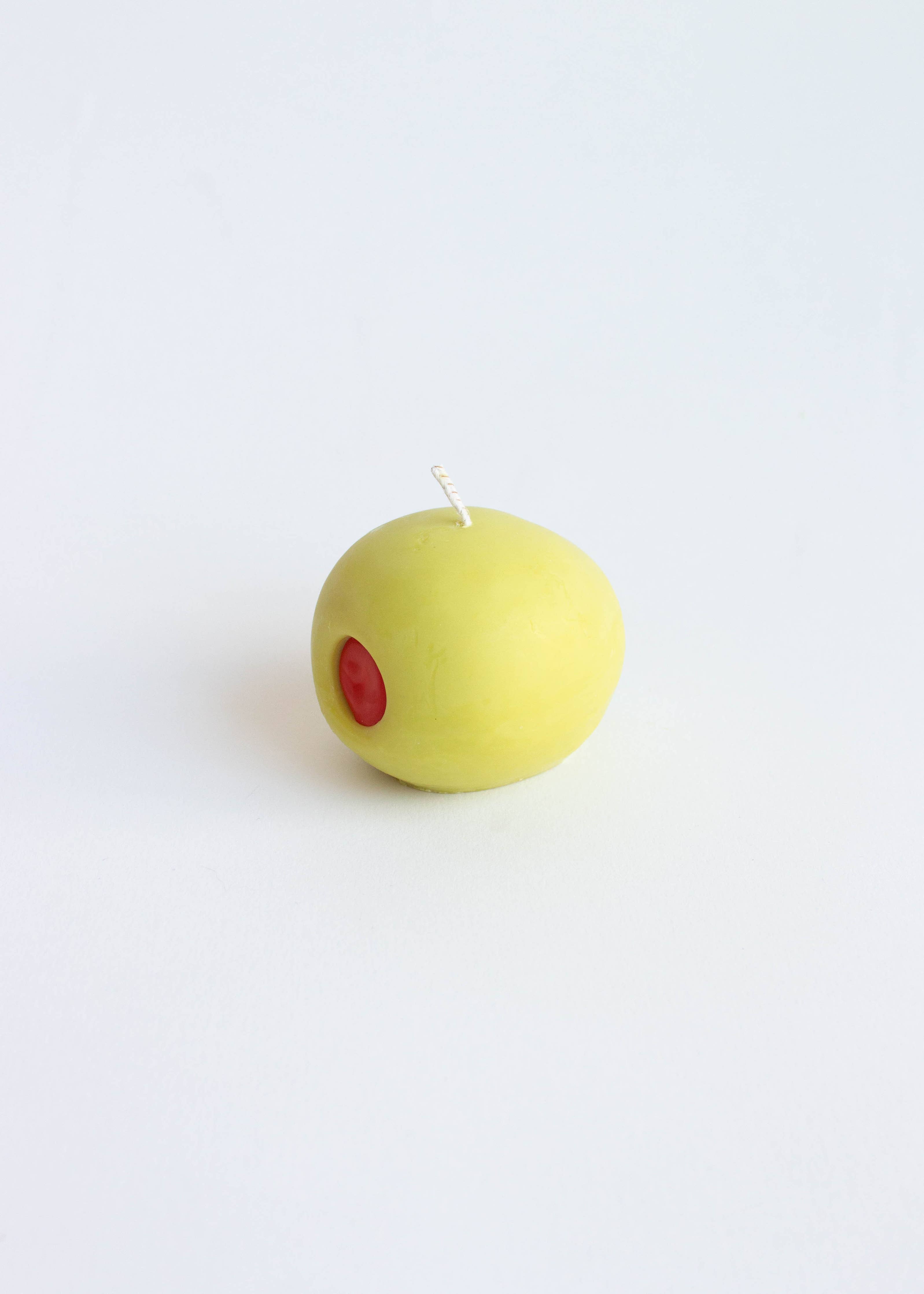 Light green olive candle with a red dot on a white background