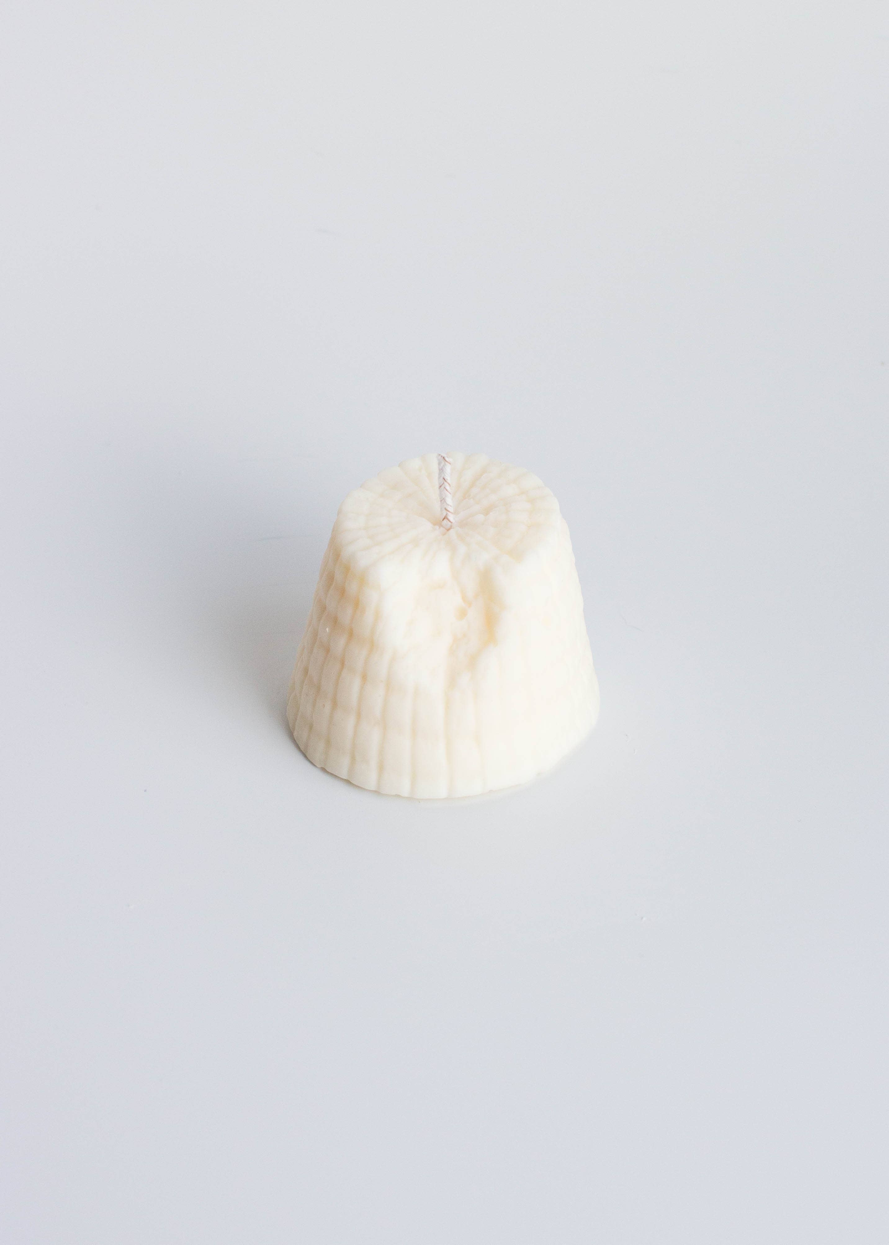 Fun Ricotta cheese shaped candle on a white background