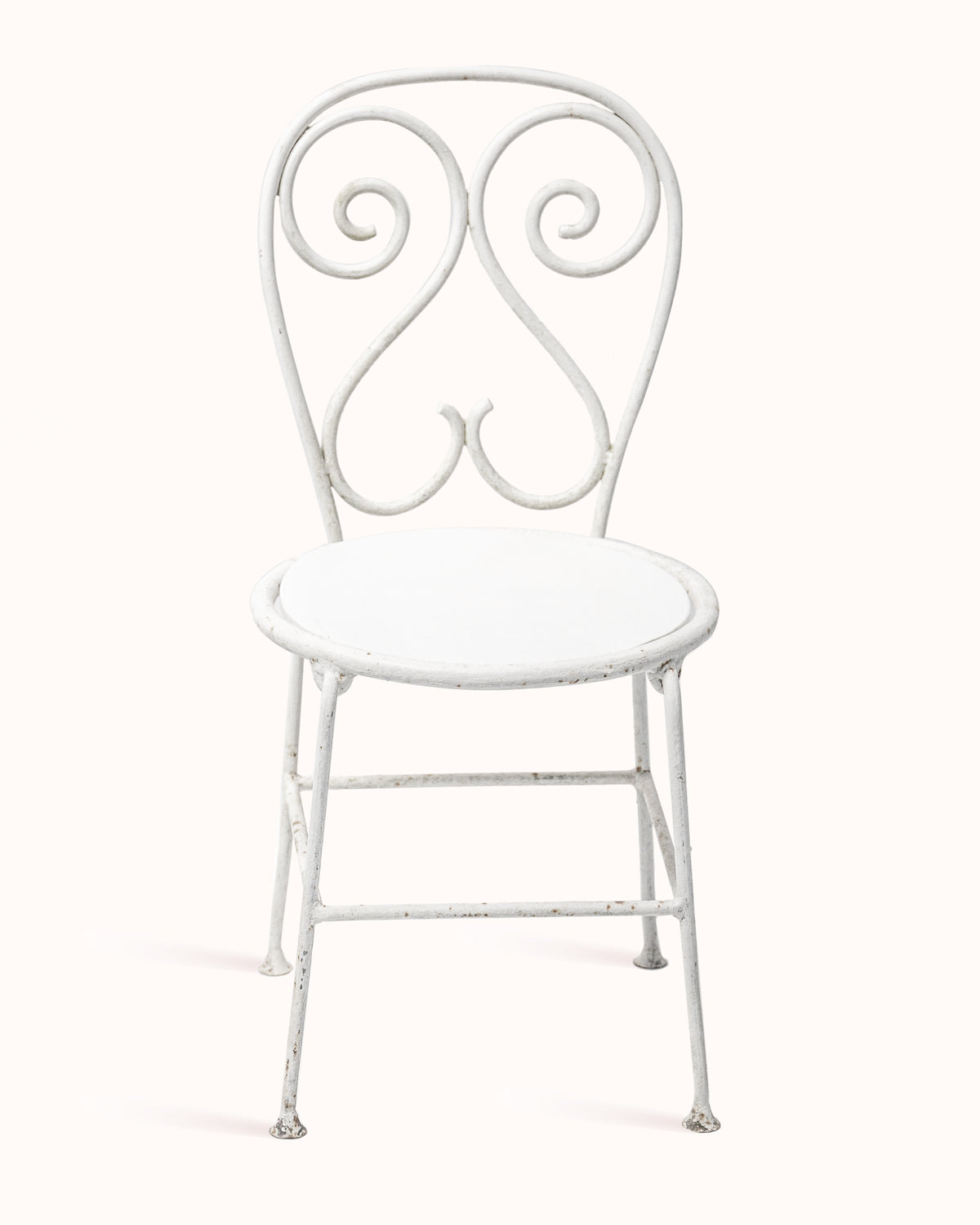 Vintage French white metal garden chair with ornate decorative backrest, displayed on a white background.