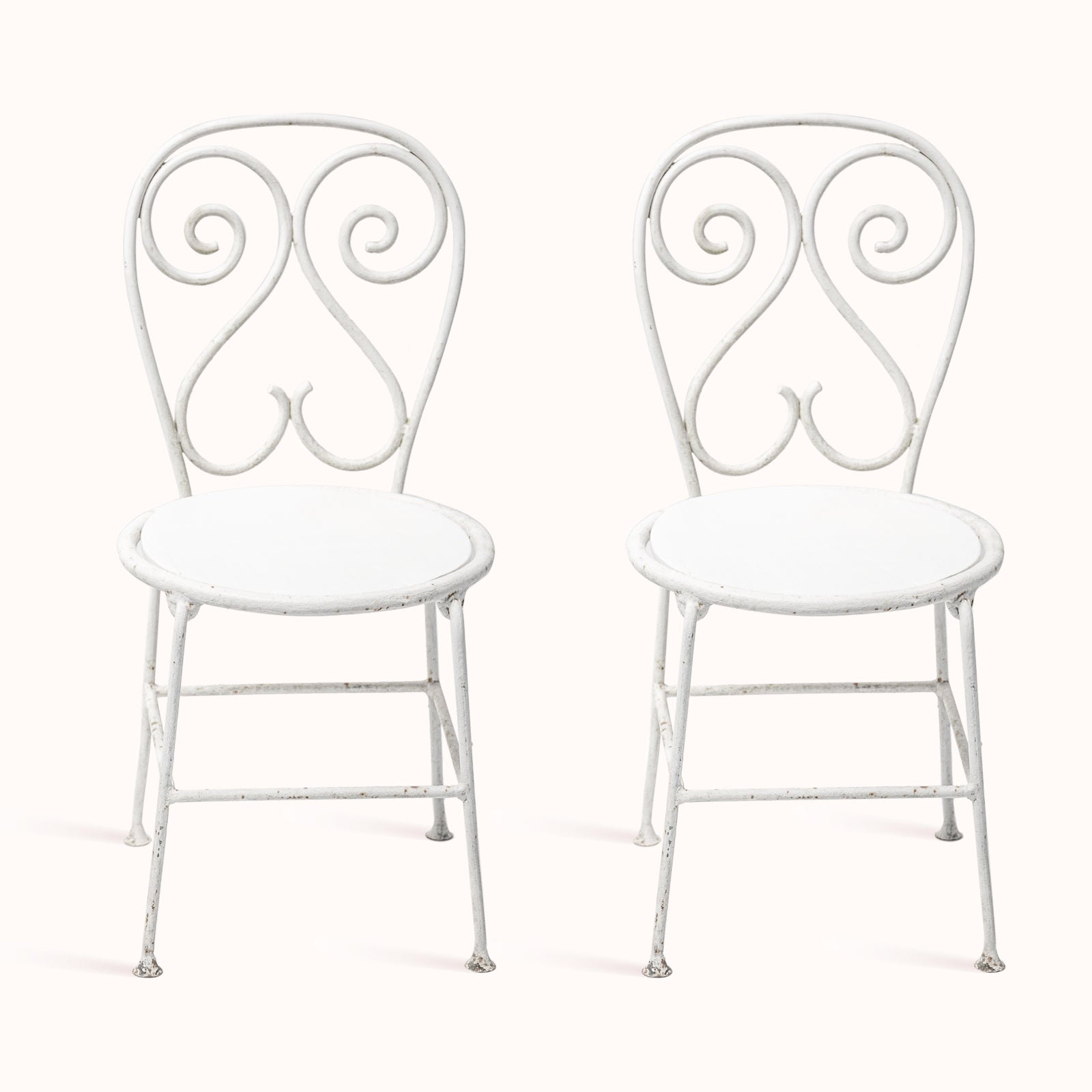 Pair of vintage French white metal garden chairs with ornate decorative backrests, displayed on a white background - from Wildschut Antiques