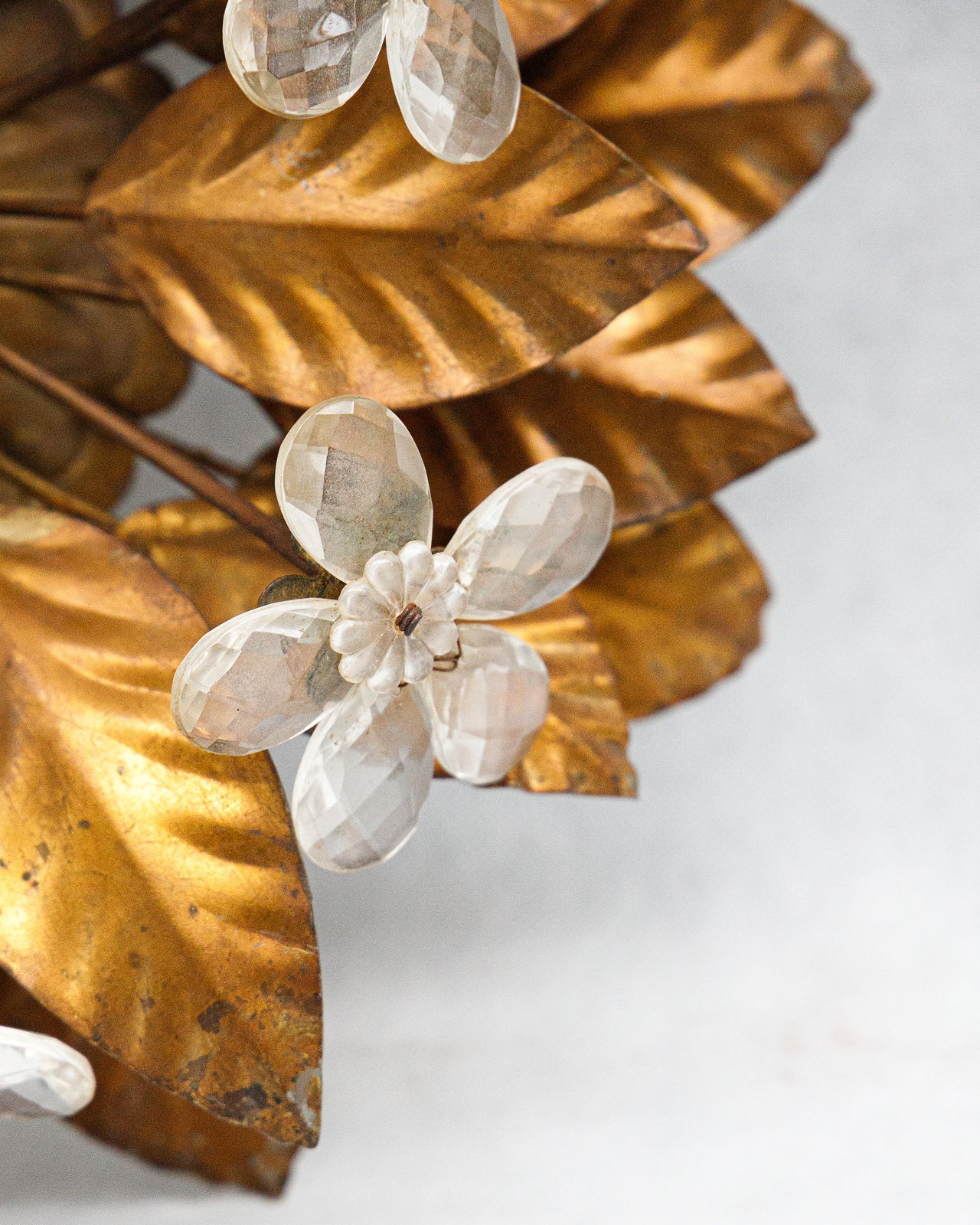 Decorative wall or ceiling mount with gold leaves and a white floral design on a light background