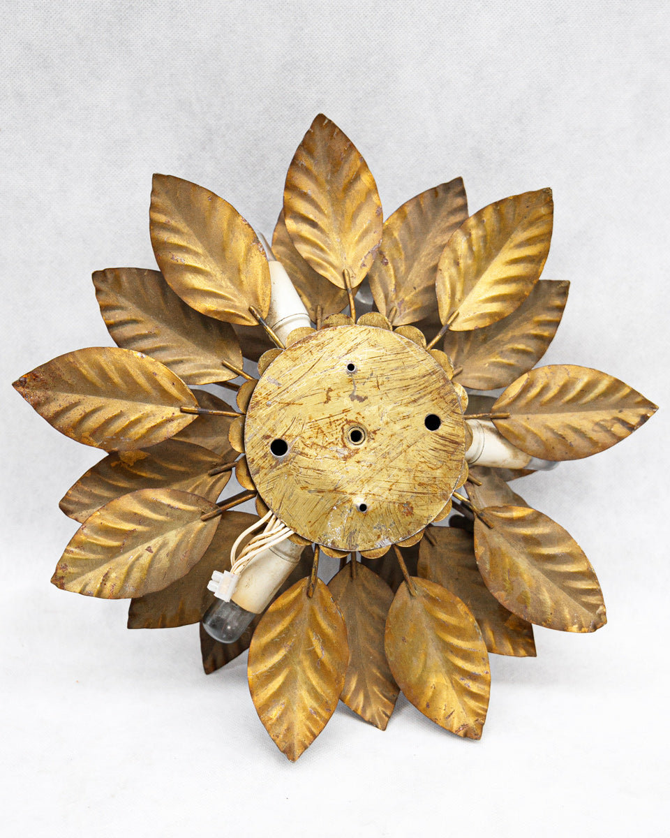 Backside of a decorative vintage French wall sconce with gold leaf design on a white background