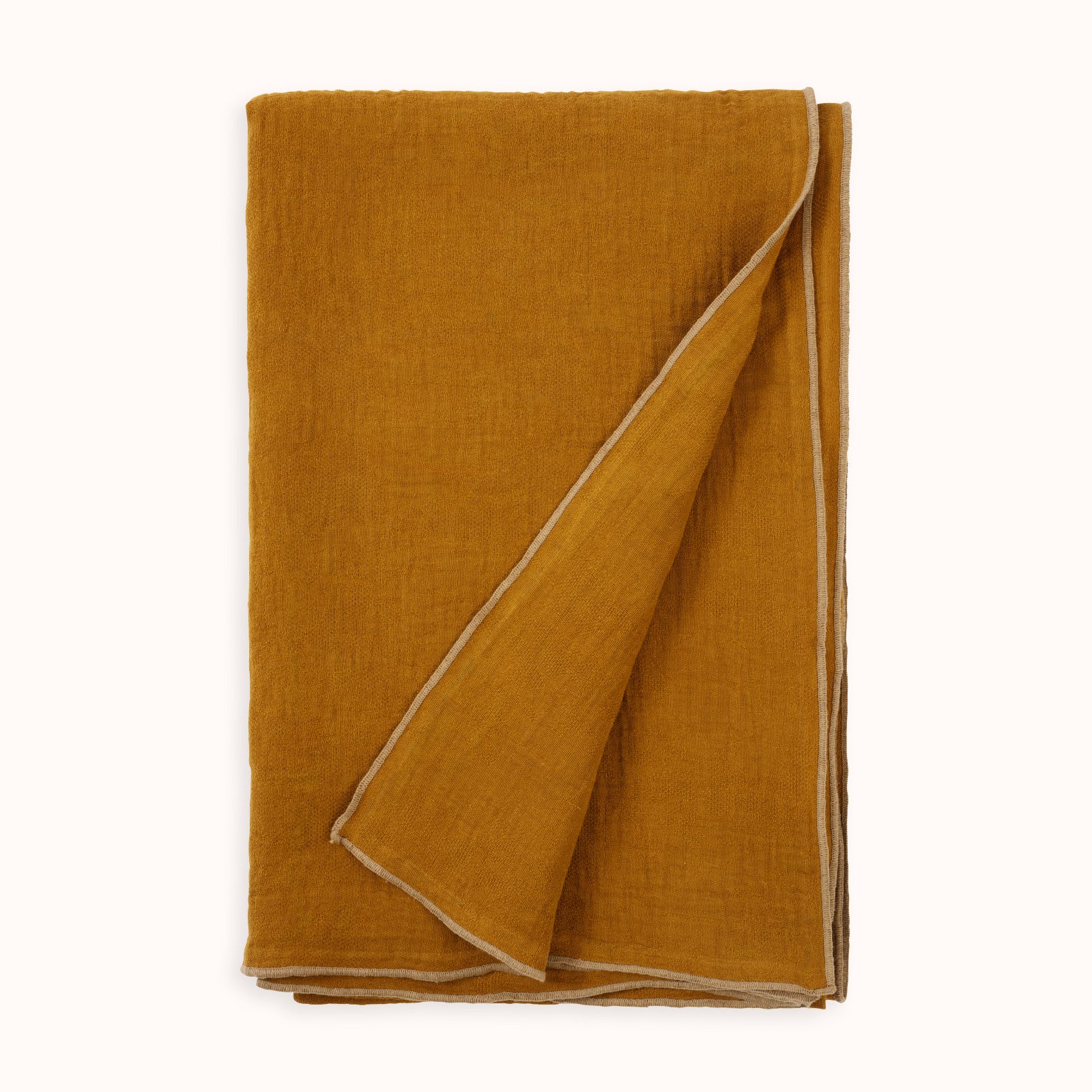 A ginger brown soft linen blend throw blanket with decorative beige seams, folded neatly and available at Wildschut Antiques