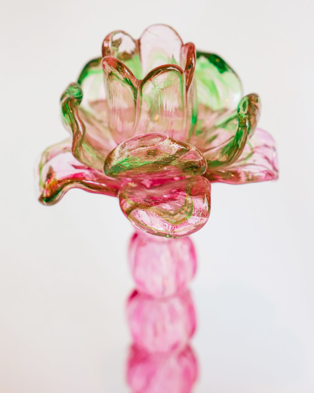 Close-up of a vintage Murano glass palm tree candle holder in green and pink colors