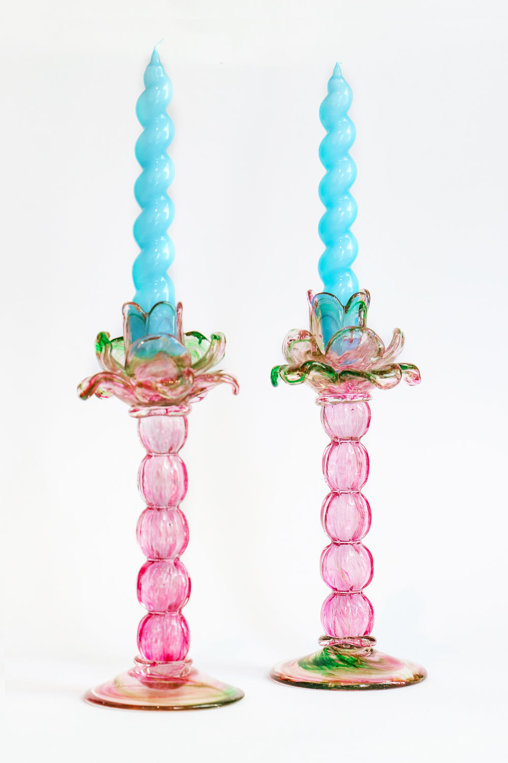 A pair of vintage Murano glass palm tree candle holders in green and pink colors with bright blue swirl candles