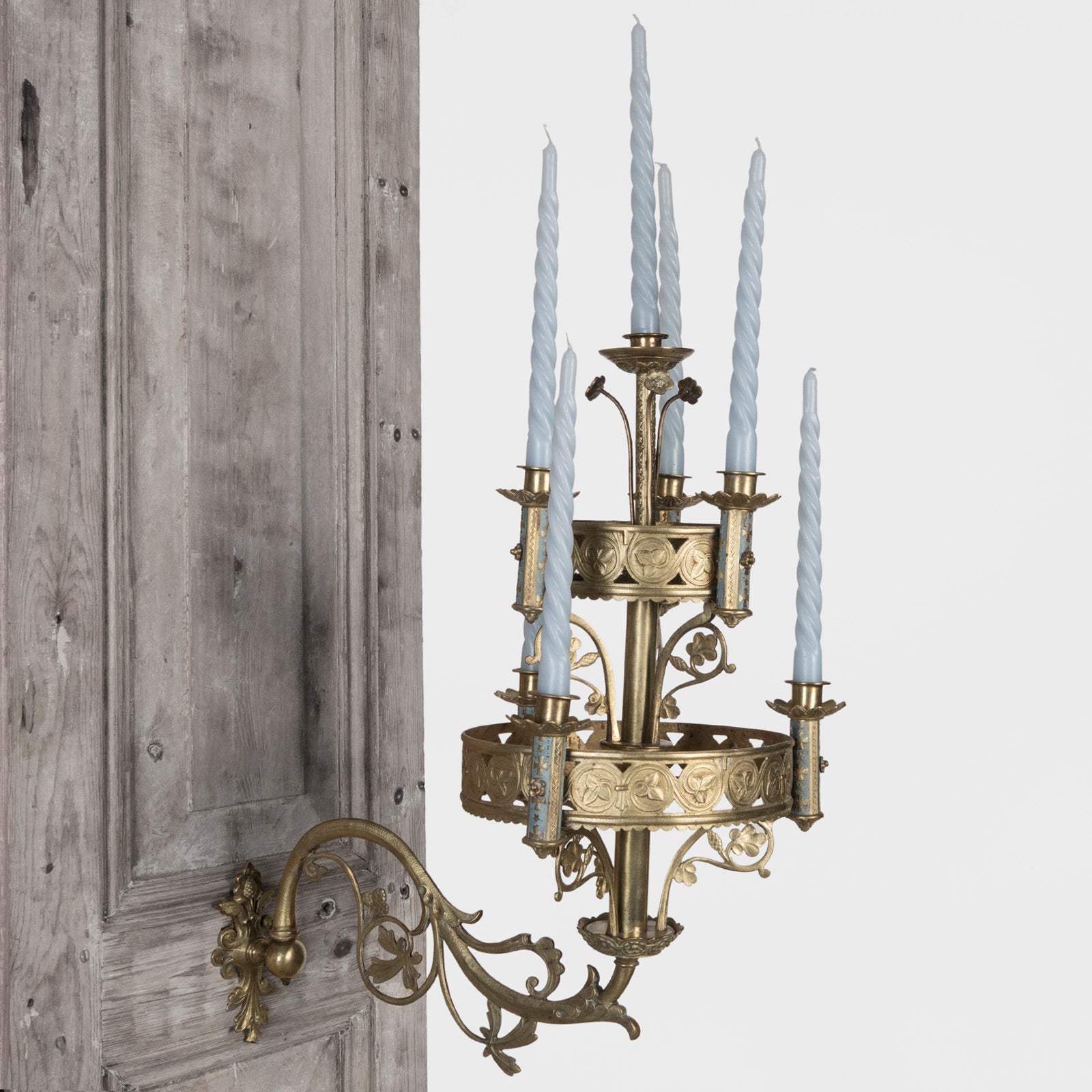 A 19th century Gothic style candle sconce with gold-colored metal mountings and light blue swirl candles, designed for wall mounting, available at Wildschut Antiques