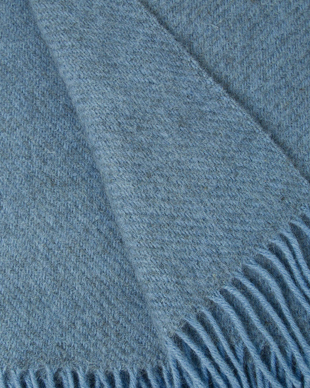 Close-up of a light blue wool throw blanket with fringed edge by Klippan 1879, available at Wildschut Antiques.