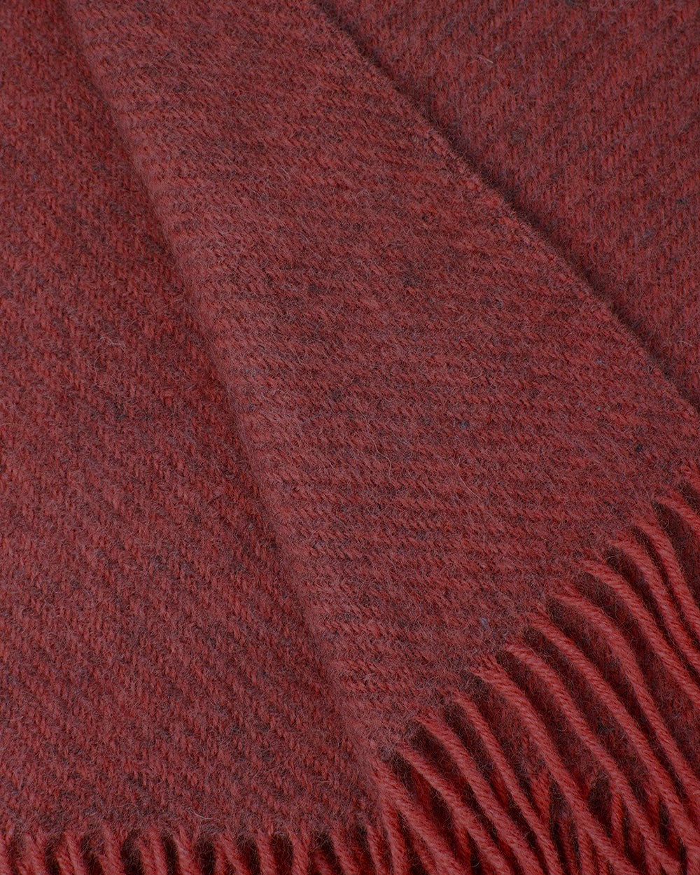 Close-up of a rust coloured wool throw blanket with fringed edge by Klippan 1879, available at Wildschut Antiques.