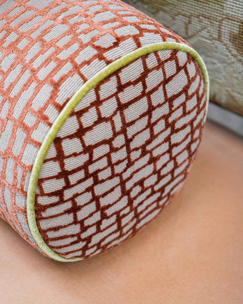 Textured cylindrical pillow with geometric pattern on a neutral background
