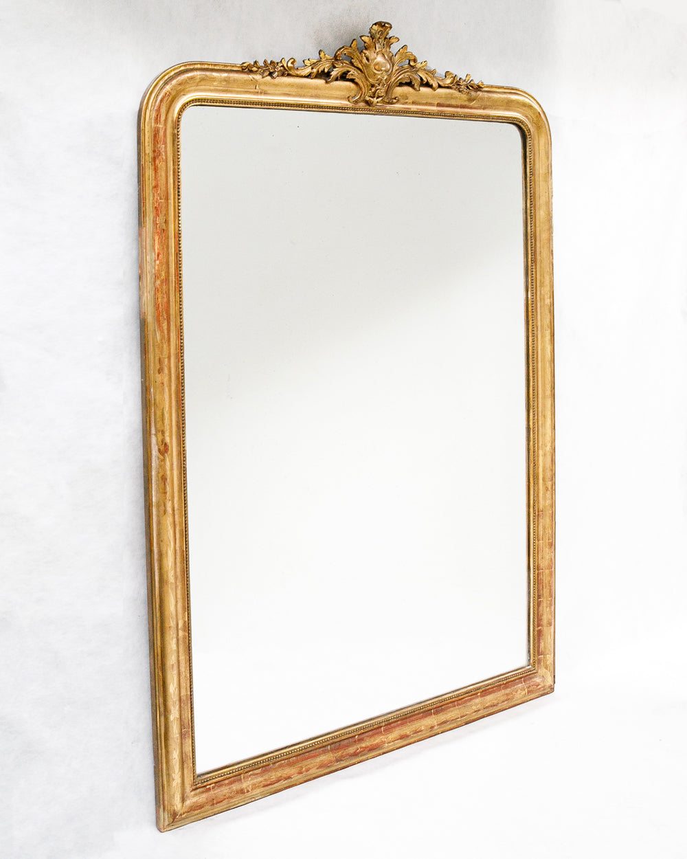 Sideview of a large antique French Louis Philippe mirror with a gilded frame and delicate floral crest, available at Wildschut Antiques