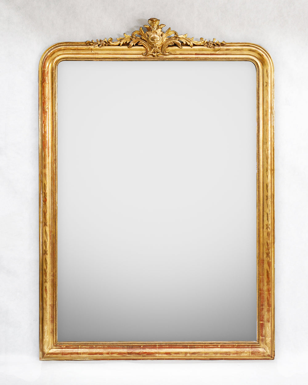 Large antique French Louis Philippe mirror with a gilded frame and delicate floral crest, available at Wildschut Antiques.