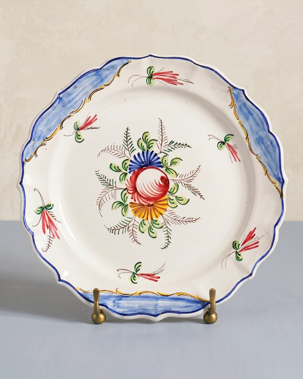Decorative vintage Italian ceramic plate with floral motif, displayed on a stand against a neutral background, available at Wildschut Antiques.