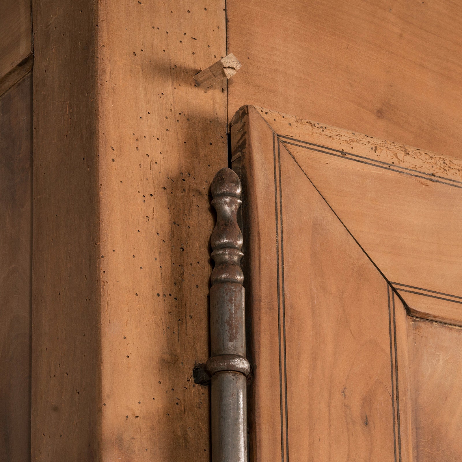 Close-up of one of the hinges of an antique French Louis Philippe style armoire made from hand-sanded cherry wood
