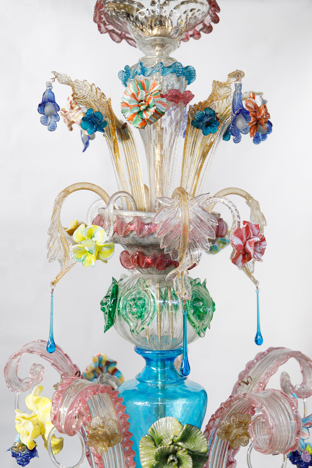 Close-up of the top part of a colorful vintage Venetian Murano glass chandelier with intricate designs on a white background, available via Wildschut Antiques