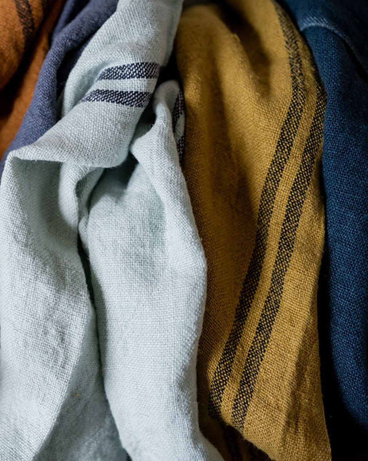 A collection of linen dish towels in soft blue, ochre and dark blue by Charvet Editions available at Wildschut Antiques
