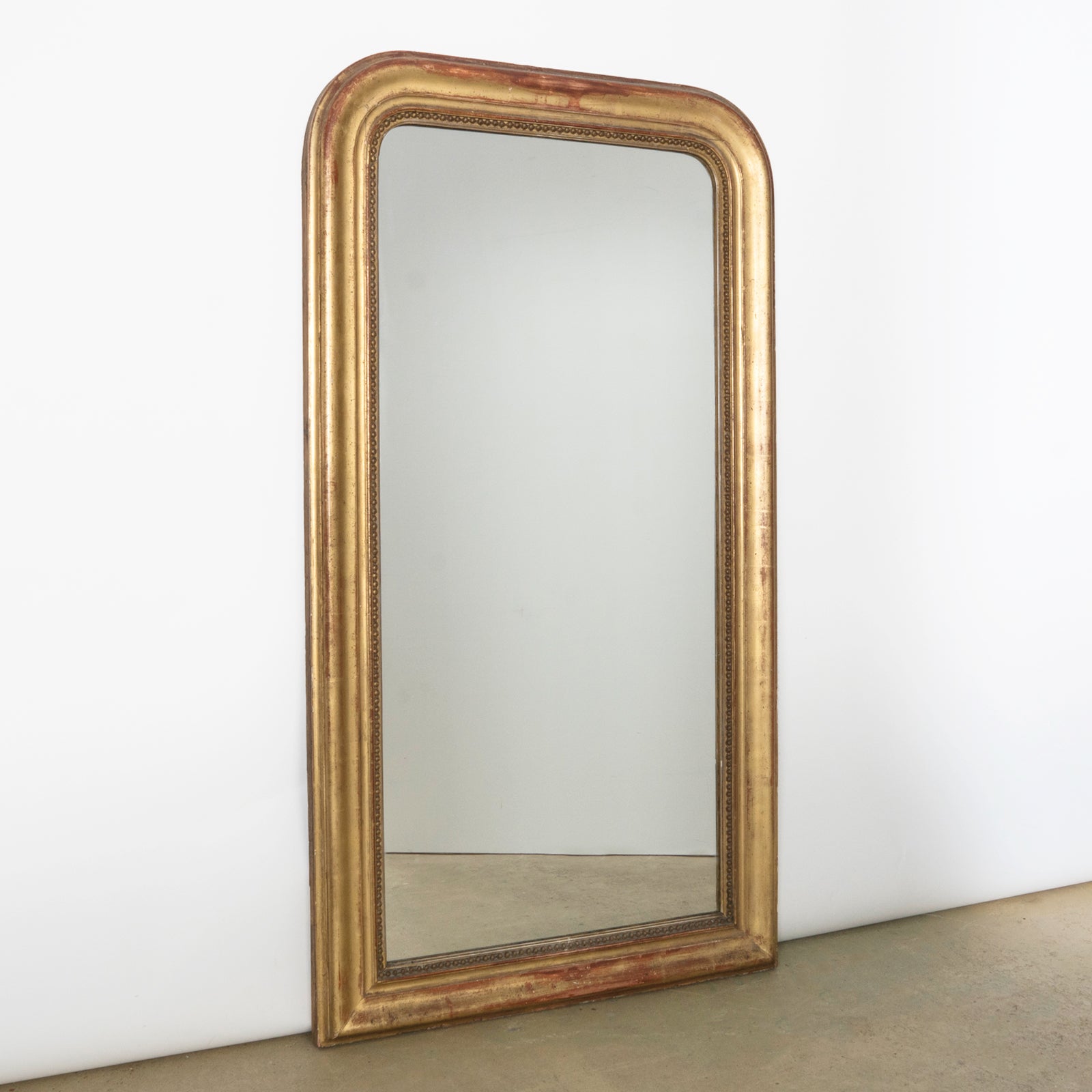 French antique Louis Philippe style mirror with a warm red glow
