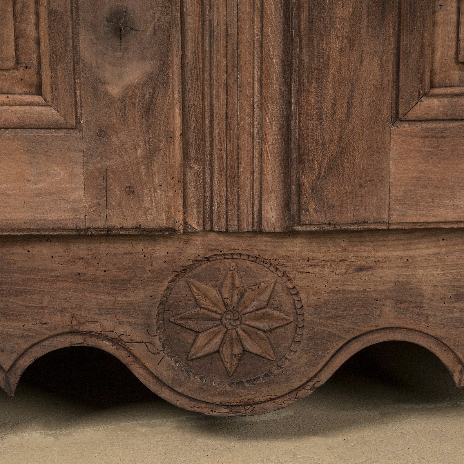 Close-up of a 19th C Antique French Louis XV style armoire with double doors and rustic wooden texture and star motif carving