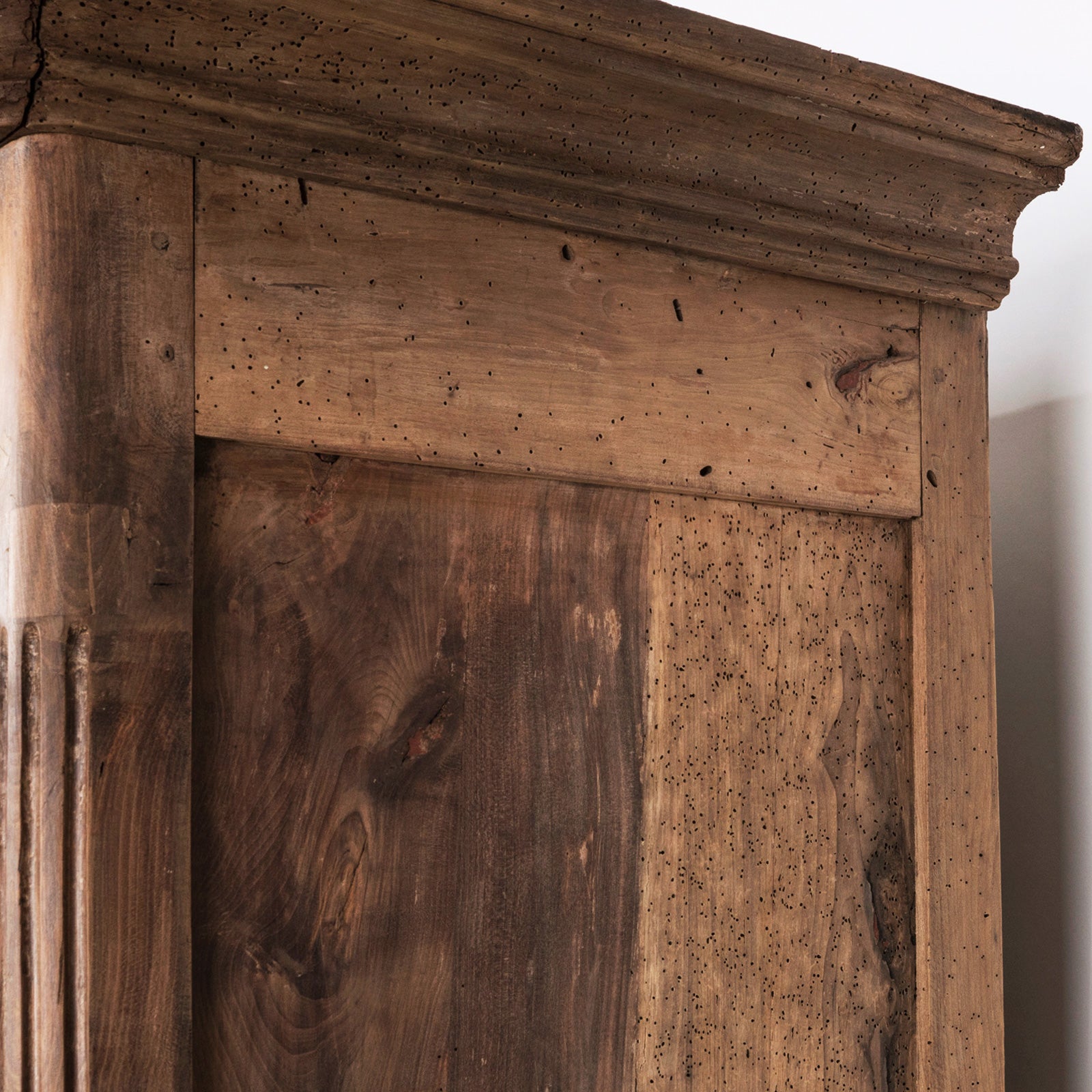 Close-up of a 19th C Antique French Louis XV style armoire with double doors and rustic wooden texture