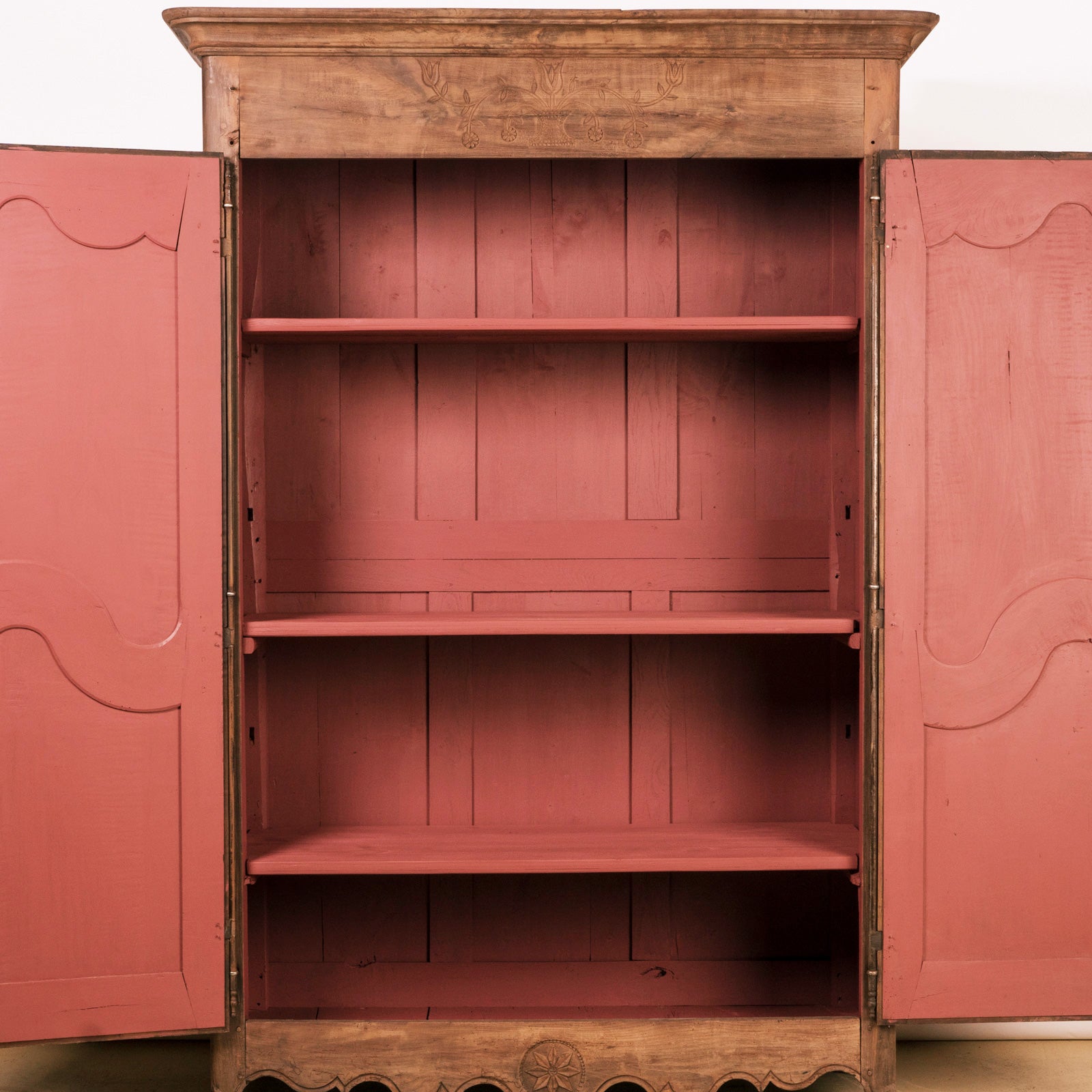 Close-up of a 19th C Antique French Louis XV style armoire with double doors and rustic wooden texture and red painted interior