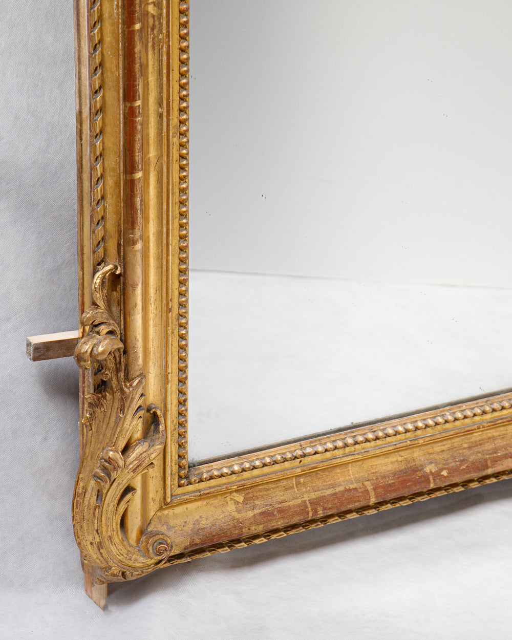 Close-up of a floral corner ornament of an antique French gold gilt mirror with a foliage crest at the top
