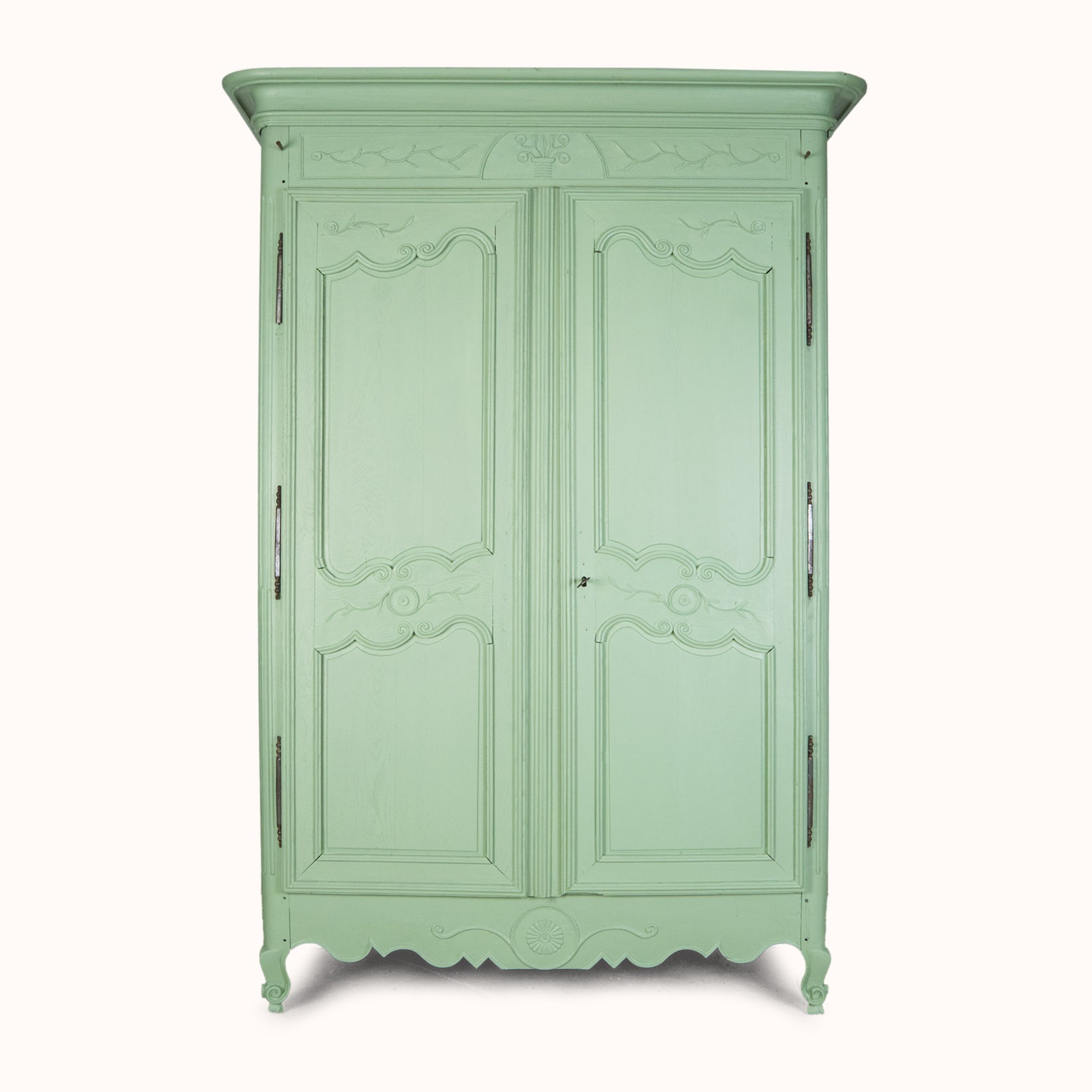 A restored soft green painted French marriage armoire from the 19th century with carved foliage motifs and steel barrel hinges, available at Wildschut Antiques
