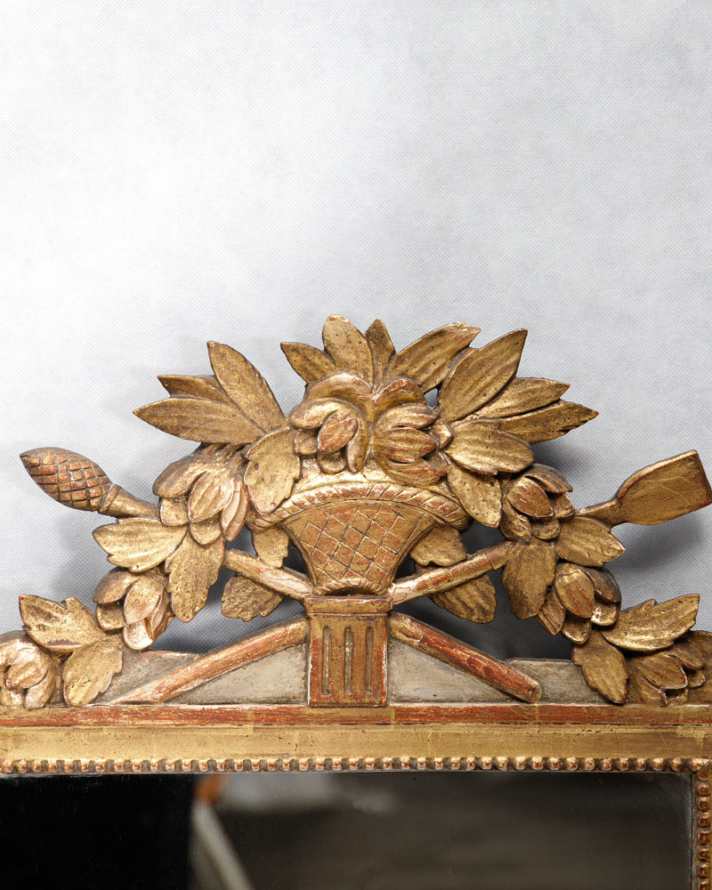 Close-up of a French Louis XVI period giltwood trumeau mirror with a finely carved crest featuring a flower-filled basket