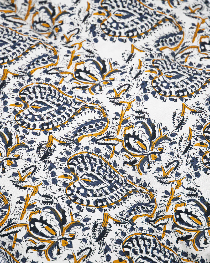 Patterned fabric with blue and ochre paisley and floral design on a white background