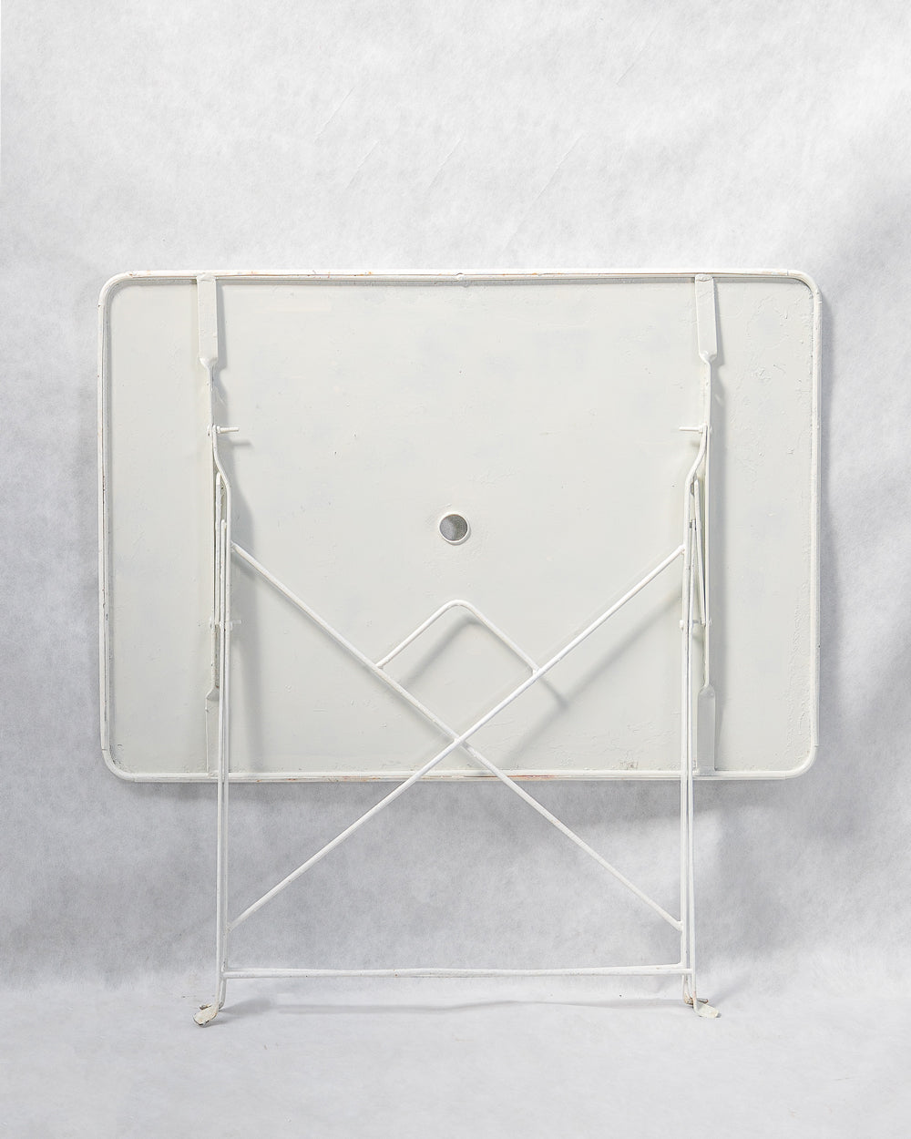 A folded vintage French white rectangular metal garden table with a collapsible frame.