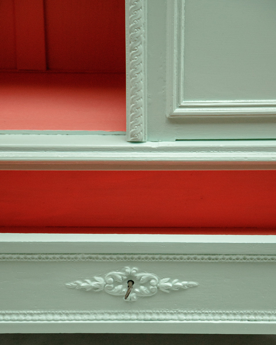 Close-up of the drawer of a French Louis XVI-style vitrine cabinet with a soft mint green finish and a contrasting red interior, intricate detailing.