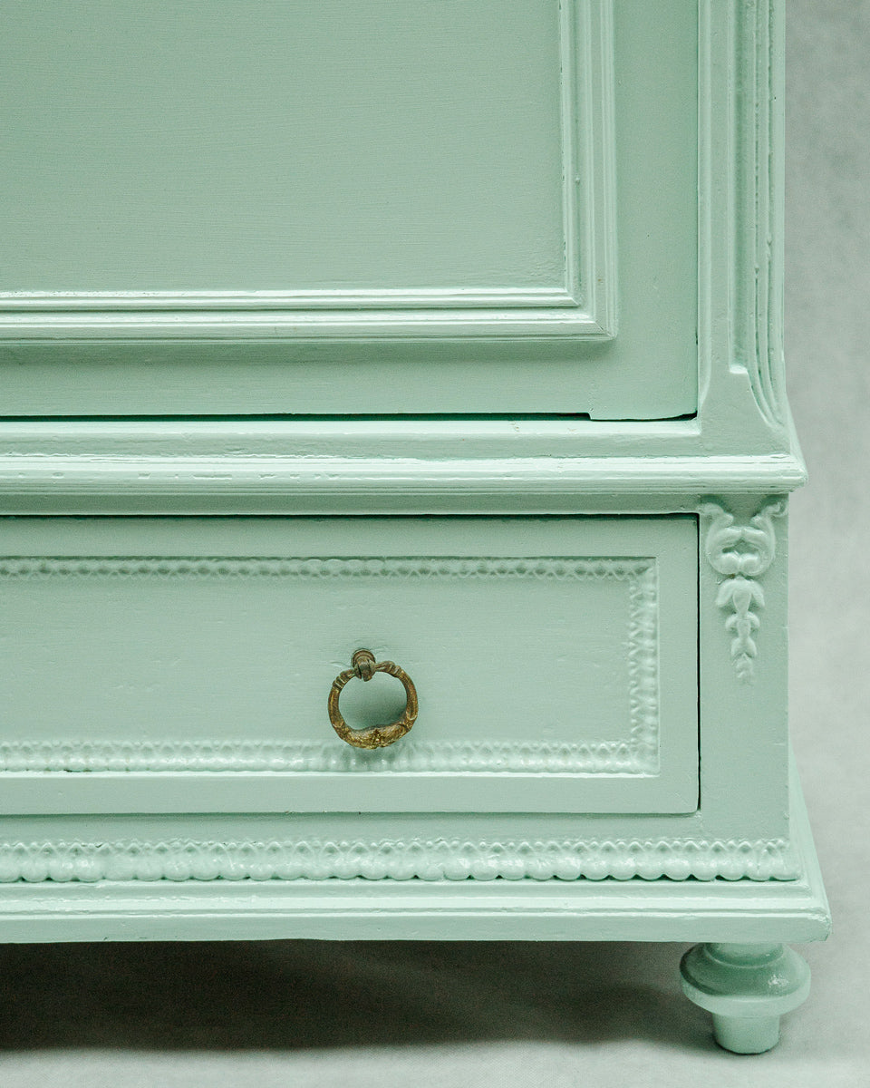 Mint green dresser with gold handle on a light gray background