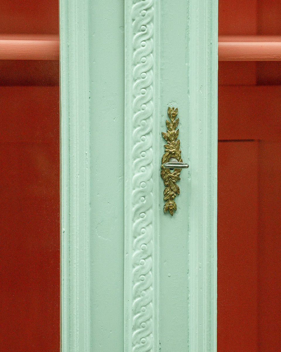 Decorative green door with gold handle against a red background