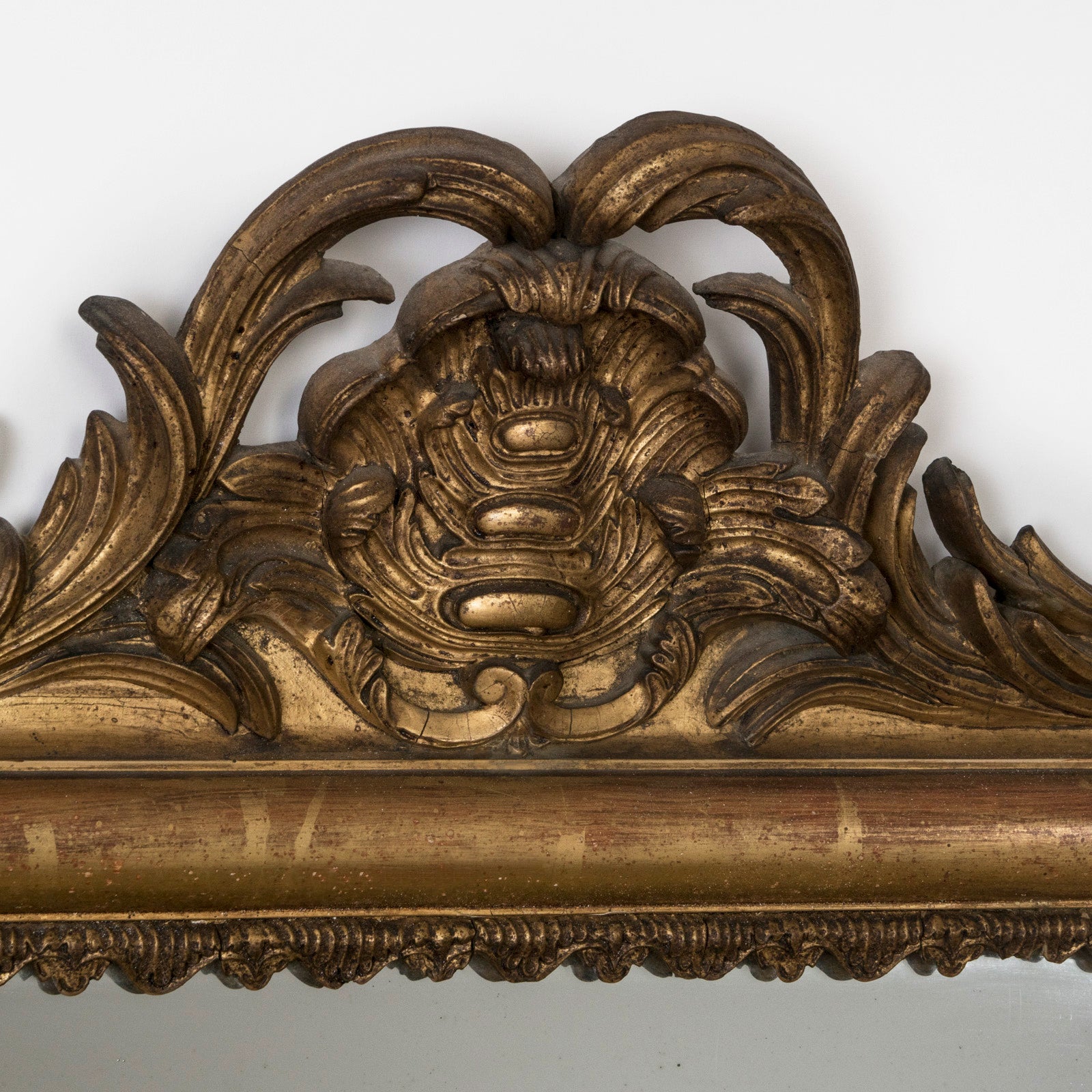 Close-up of the crest of an antique ornate Louis XV style provincal mirror with a gold carved frame
