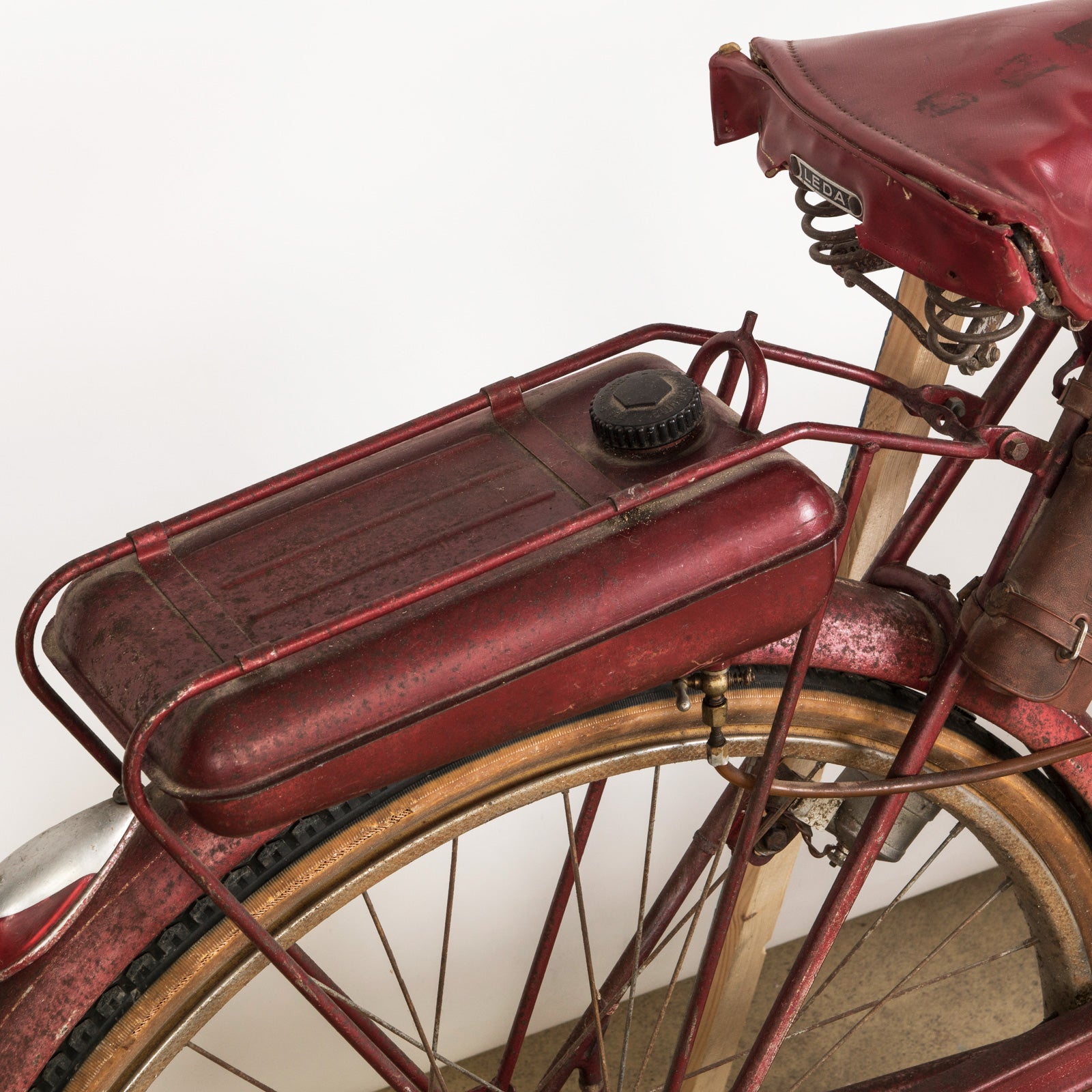 Close-up of the gas tank of a vintage French Mobylette motorcycle, type Mosquito, with a red body and red seat, featuring a great patina finish and original mechanisms