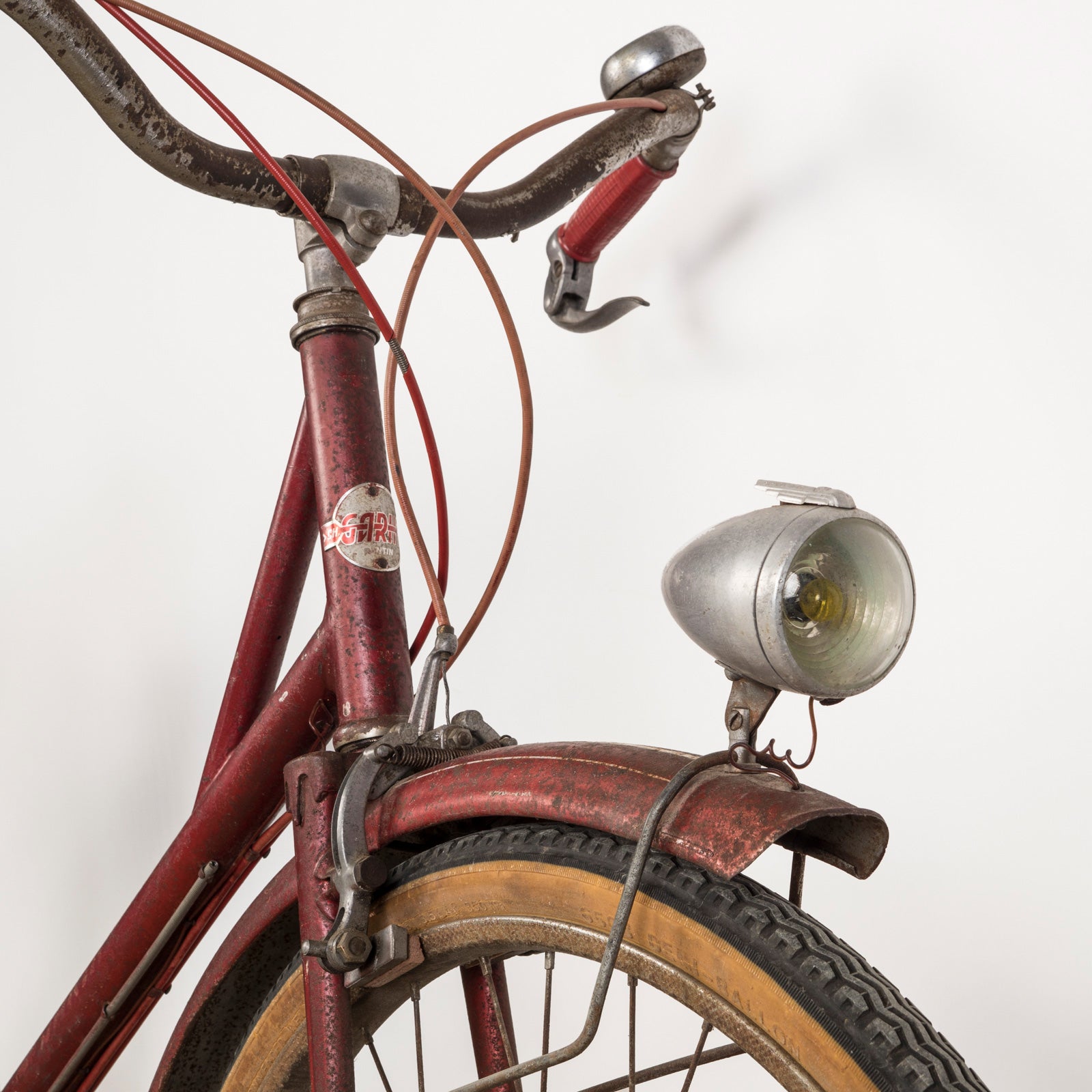 Close-up of the front part of a vintage French Mobylette motorcycle, type Mosquito, with a red body and red seat, featuring a great patina finish and original mechanisms