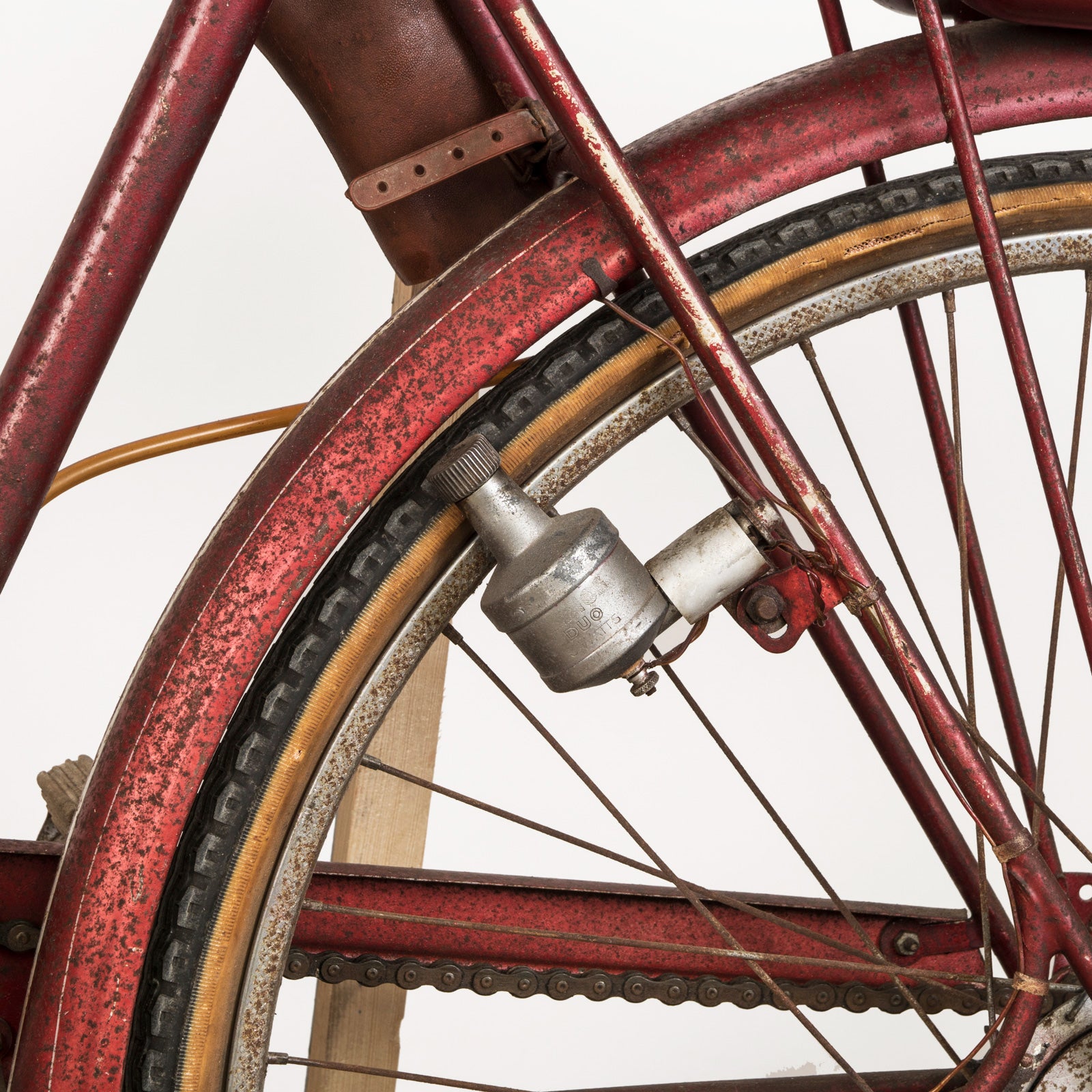 Close-up of a wheel of a vintage French Mobylette motorcycle, type Mosquito, with a red body and red seat, featuring a great patina finish and original mechanisms