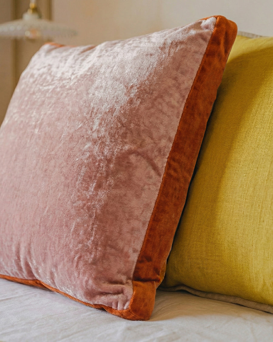Close-up of a pink and yellow pillow on a bed.