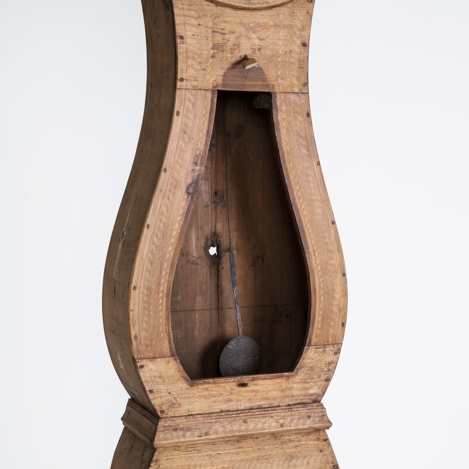 Close-up of the bellly of an antique Swedish Mora clock with a natural finish