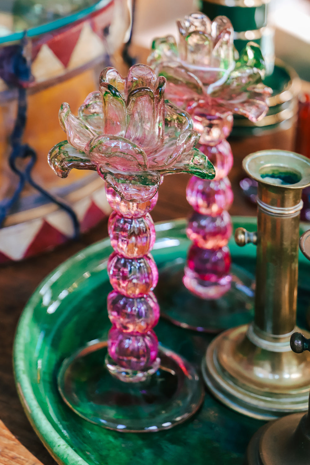 A pair of vintage Murano glass palm tree candle holders in green and pink colors, displayed on a emerald green platter in the store of Wildschut Antiques